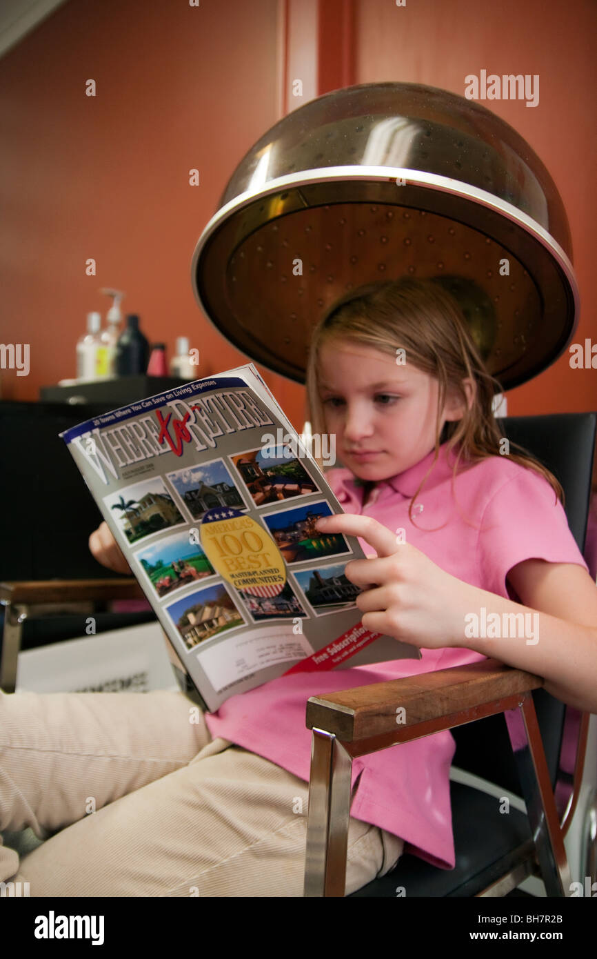 Little girl catching up on her reading at beauty shop Stock Photo