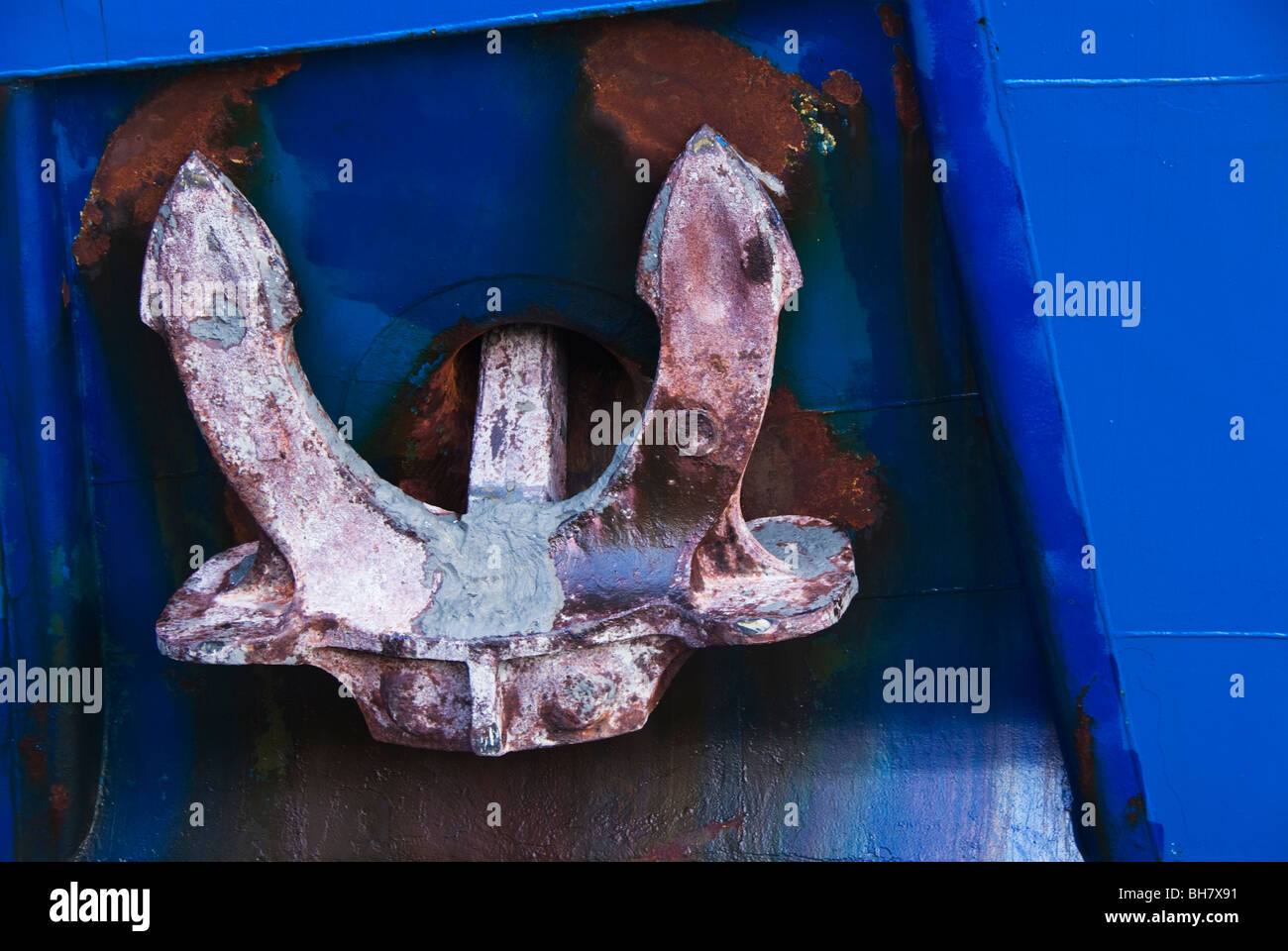 A close - up view of a ship's anchor housed in it's hawse pipe recessed in the hull. Stock Photo