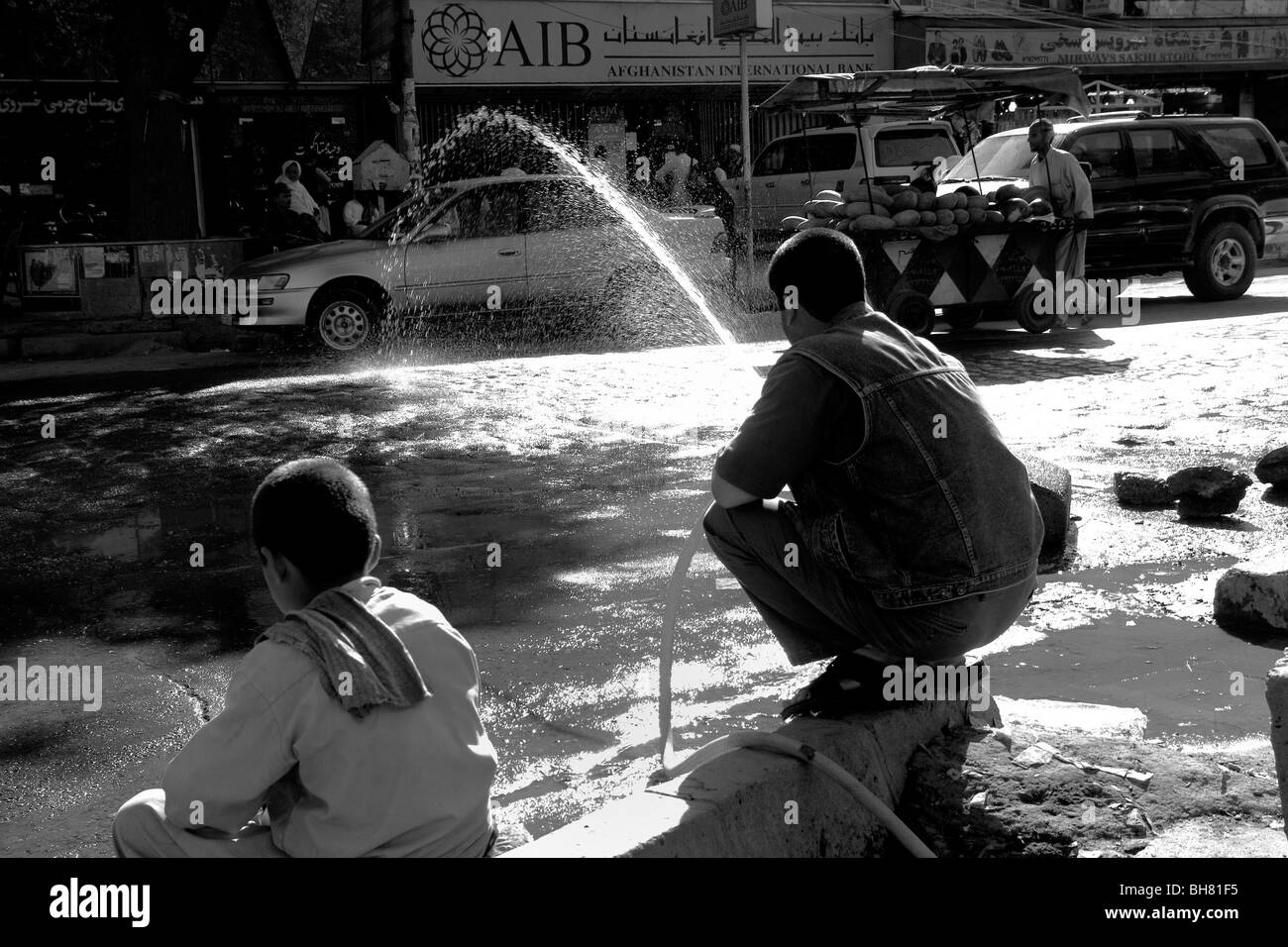 Afghan sprays water on to street in a bid to keep the dust at bay in Kabul Afghanistan Stock Photo