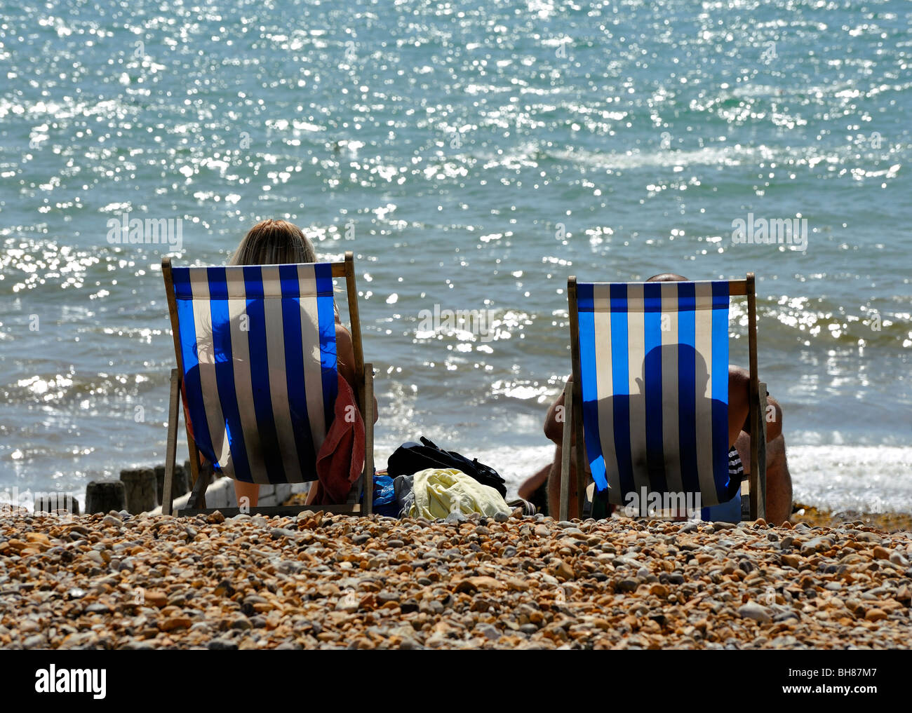 OLDER COUPLE ON PEBBLE BEACH SOUTH COAST OF ENGLAND Stock Photo