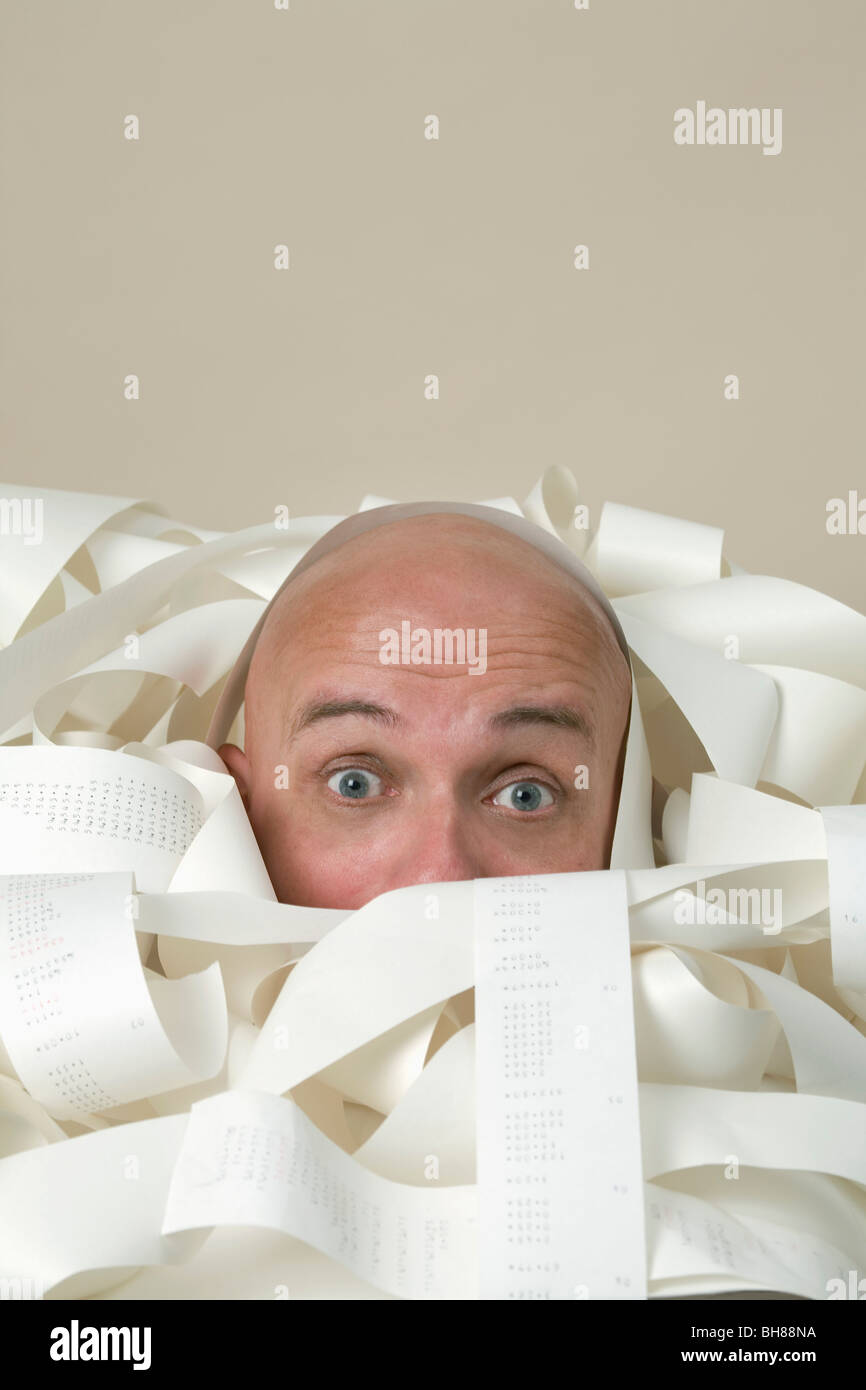 Detail of a man buried in printed receipts Stock Photo