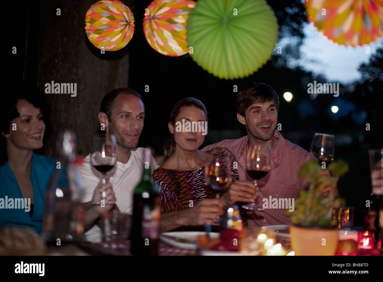 Four people at a dinner raising their wineglasses in a toast Stock Photo
