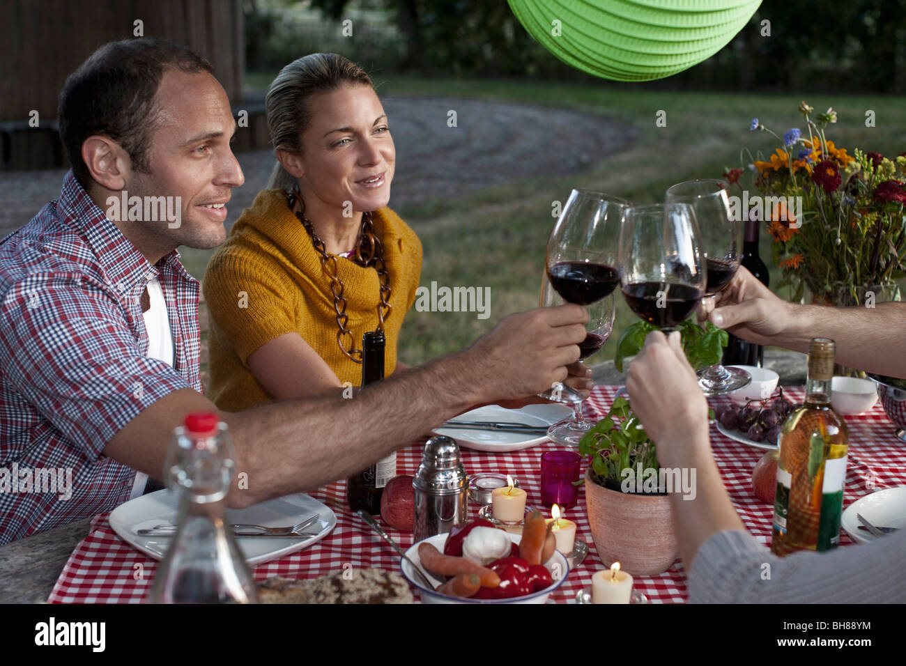 Four people at a dinner raising their wineglasses in a toast Stock Photo