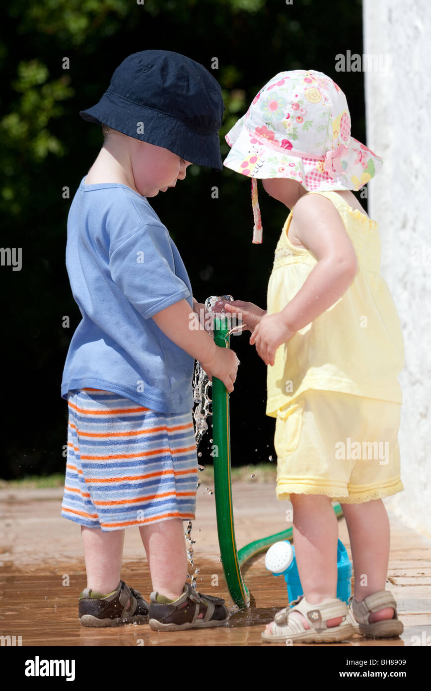 Toddlers playing with a hose pipe. Stock Photo