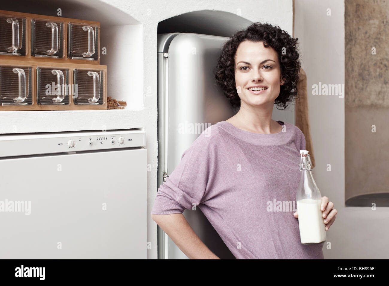 A woman holding a bottle of milk in the kitchen Stock Photo