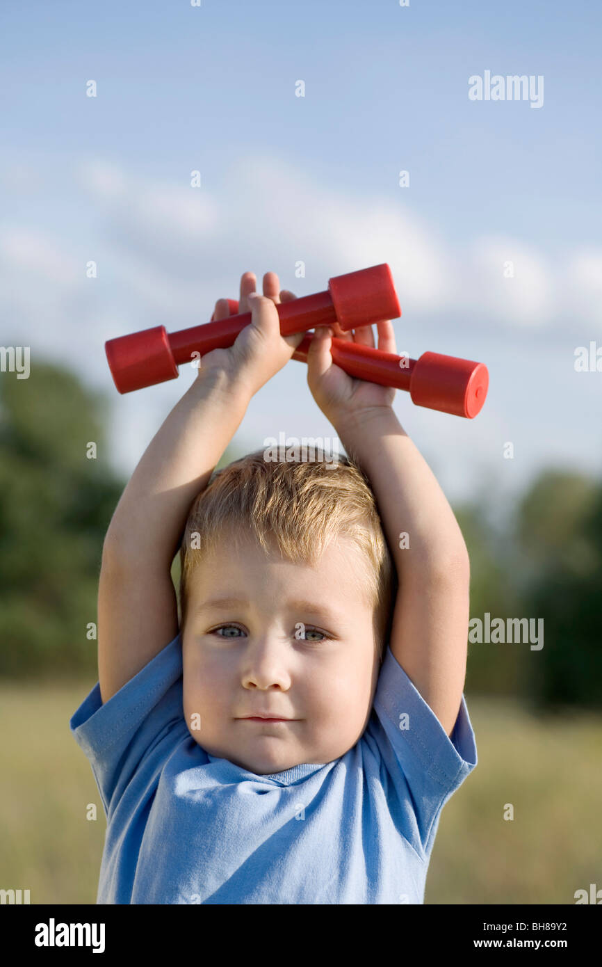 A boy holding hand weights above his head Stock Photo