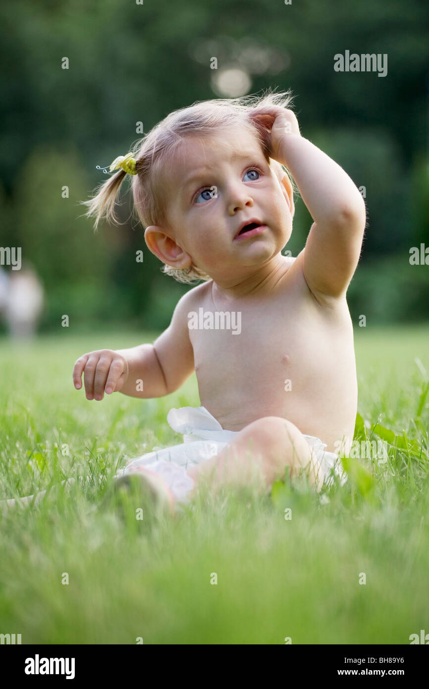 A baby girl sitting on grass in a diaper Stock Photo - Alamy
