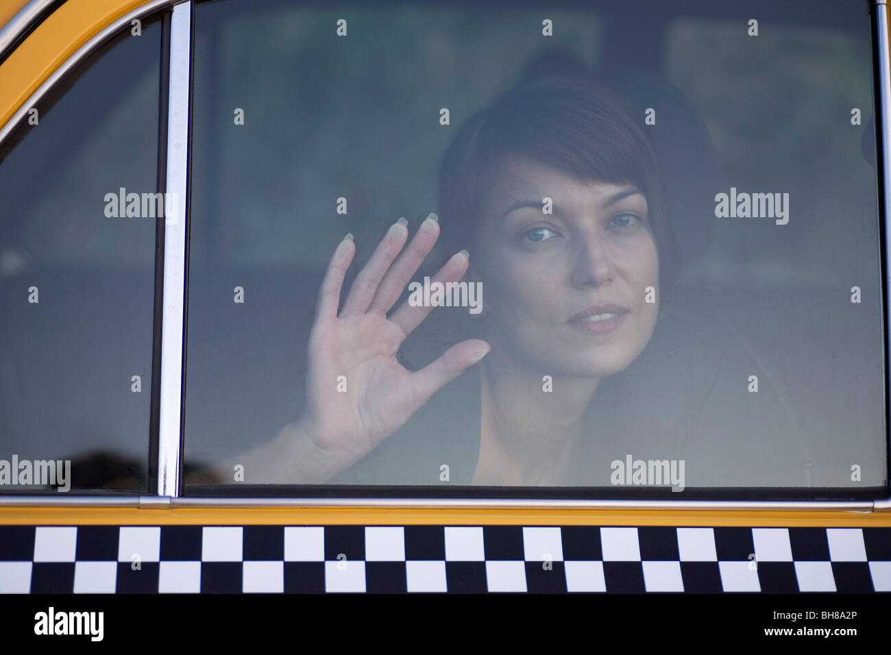 A sad woman in a taxi with her palm against the window Stock Photo