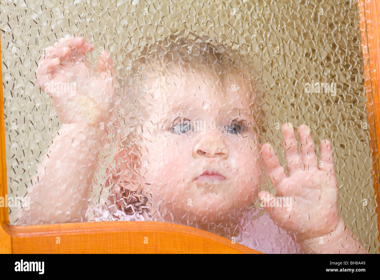 A child pressed up against a beveled glass window Stock Photo