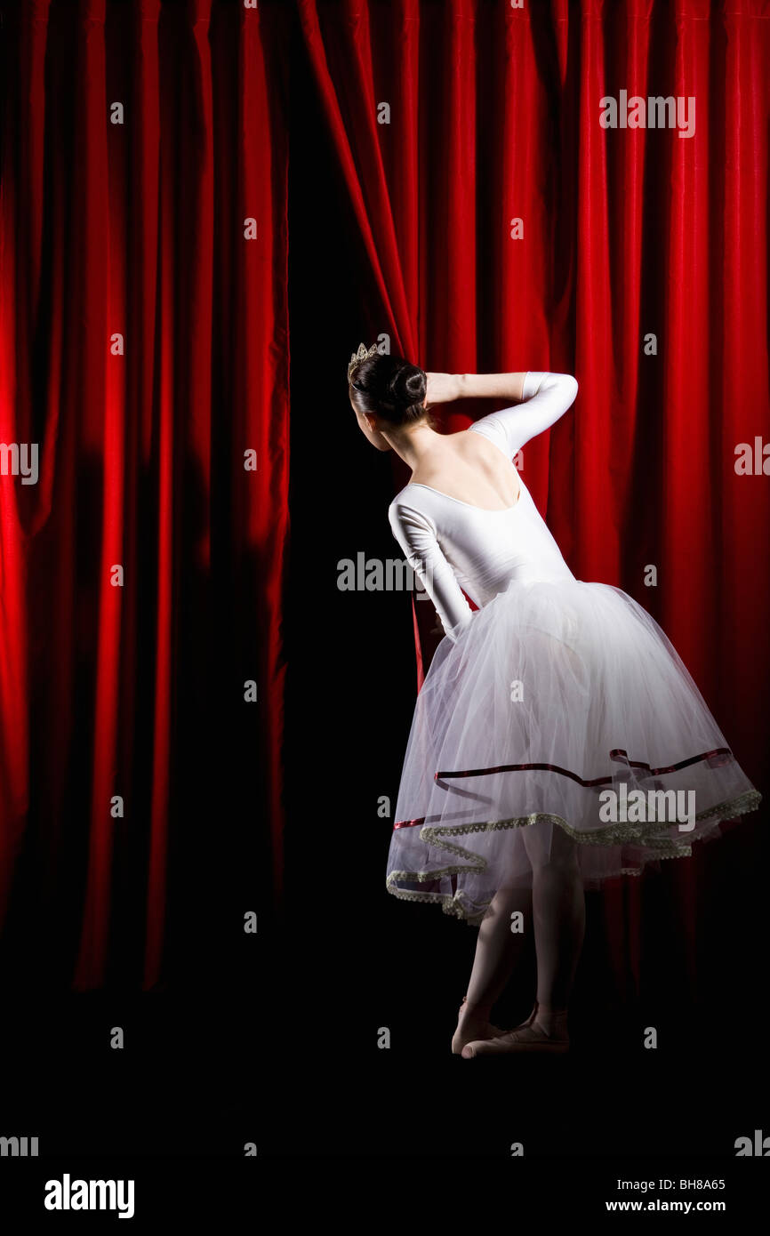 A ballet dancer peeking through a stage curtain, rear view Stock Photo