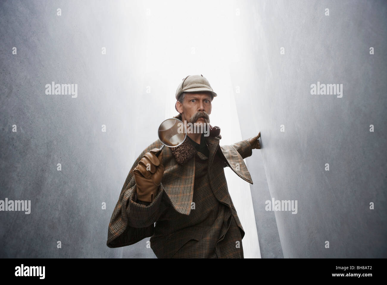 A man dressed like Sherlock Holmes holding a magnifying glass Stock Photo