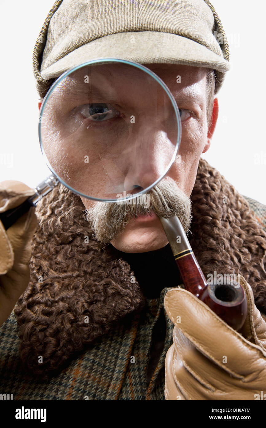 A man dressed up as Sherlock Holmes with a magnifying glass distorting his eye Stock Photo