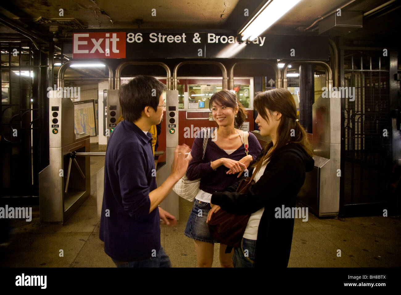 Three young Asians converse at the 86th Street station of the city's underground rapid-transit system New York Stock Photo