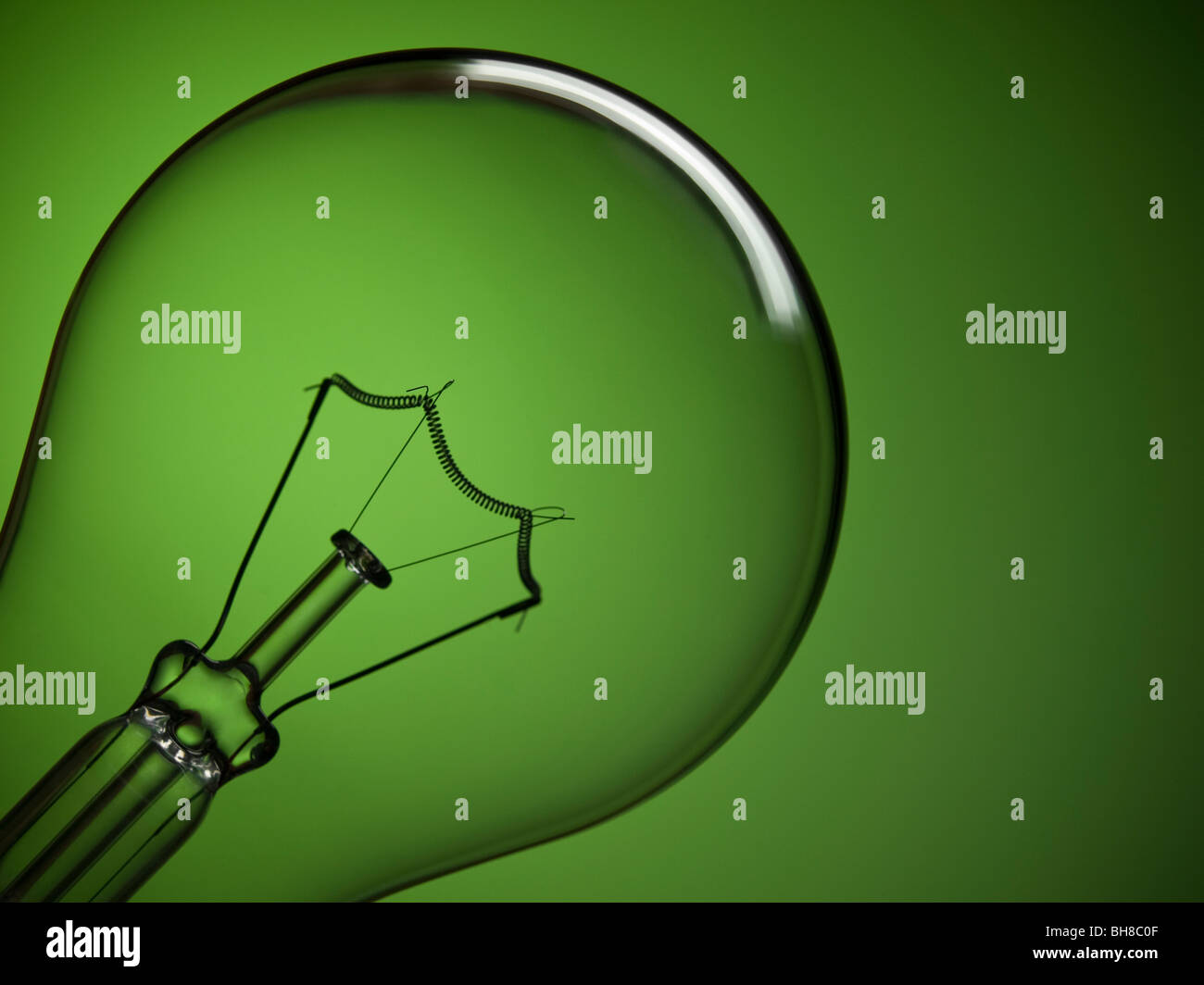 Close up on a transparent light bulb over a green background. Stock Photo