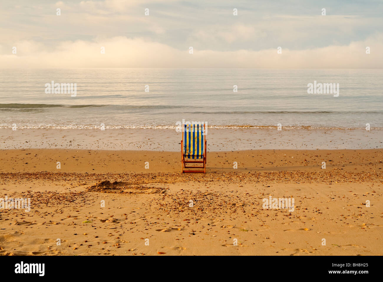 View of the sandy beach and abandoned striped wooden deckchair at Bournemouth in Dorset in south west England UK Stock Photo