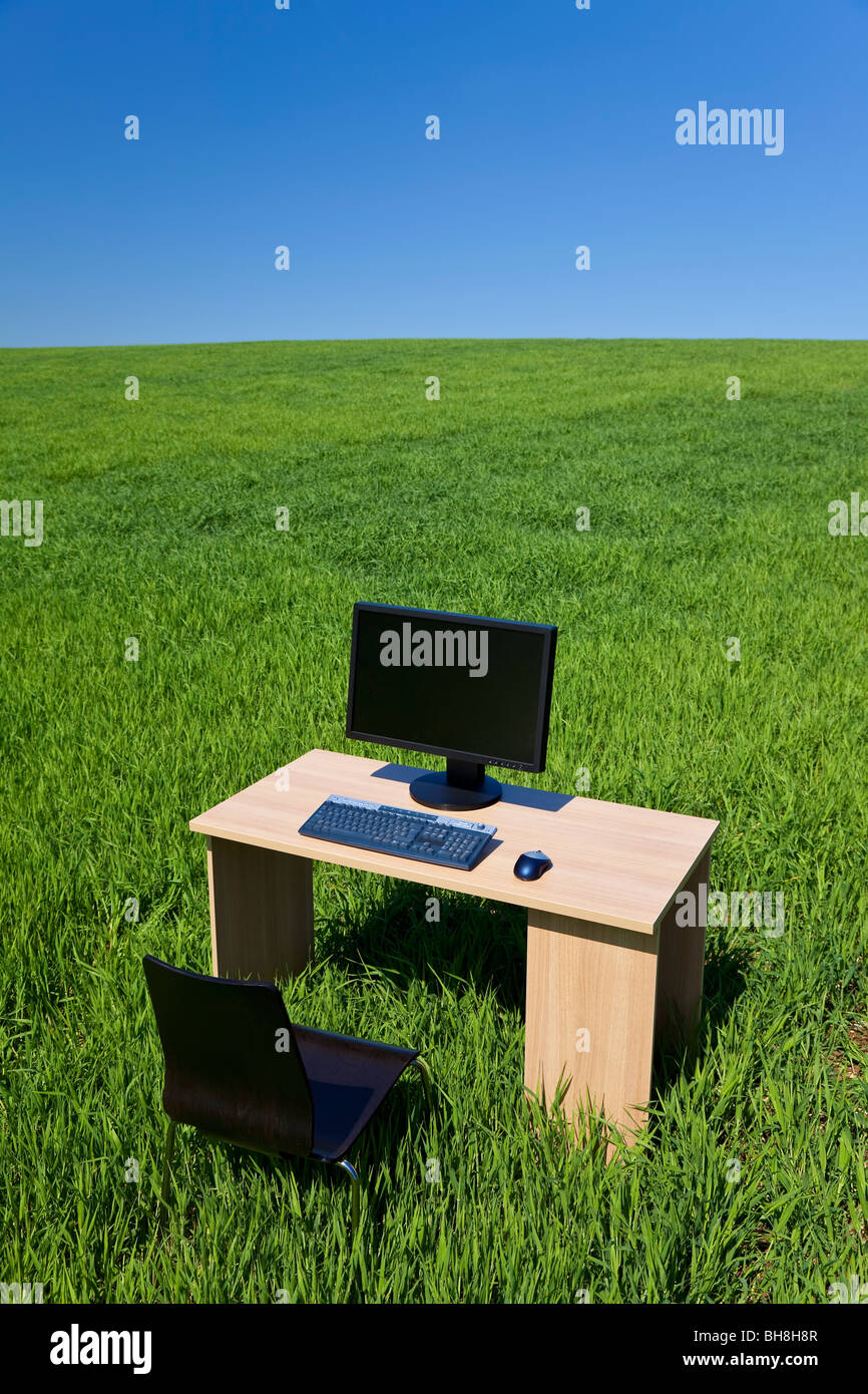 Business concept shot showing a computer on a desk in a green field ...