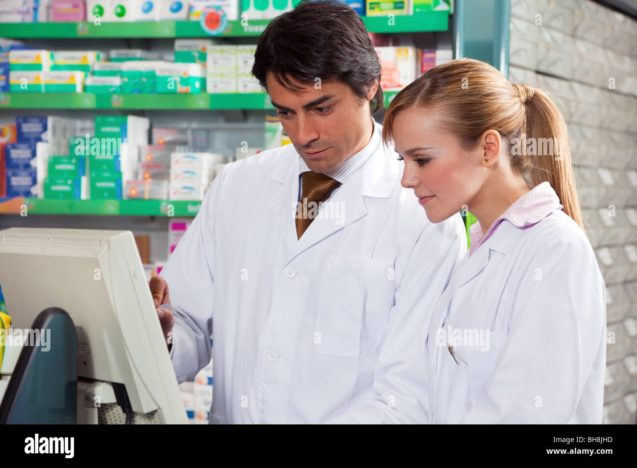 male and female pharmacists looking at computer screen Stock Photo