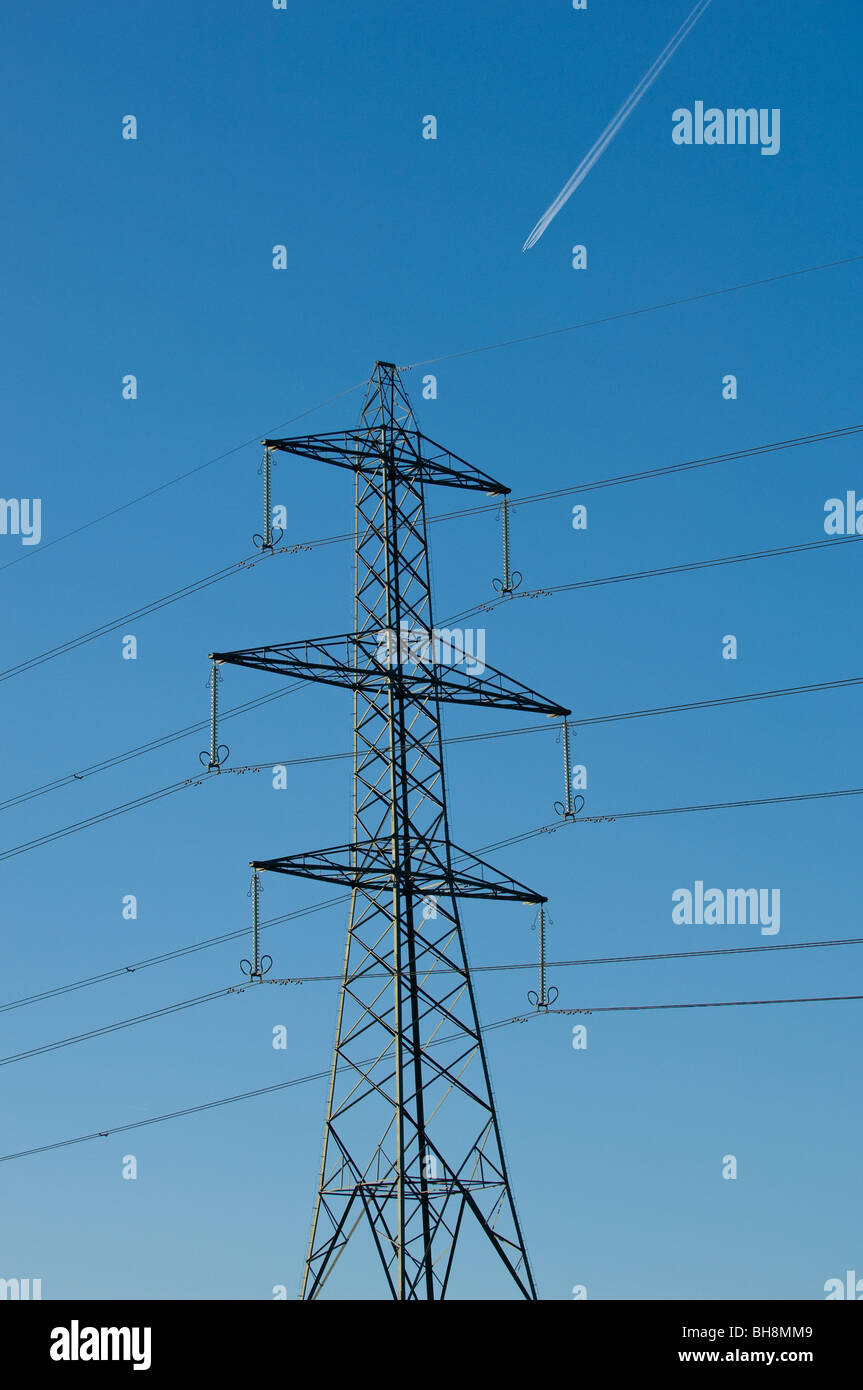 High voltage overhead transmission lines operating at 275kV with glass insulators and steel lattice support tower and jet. Stock Photo