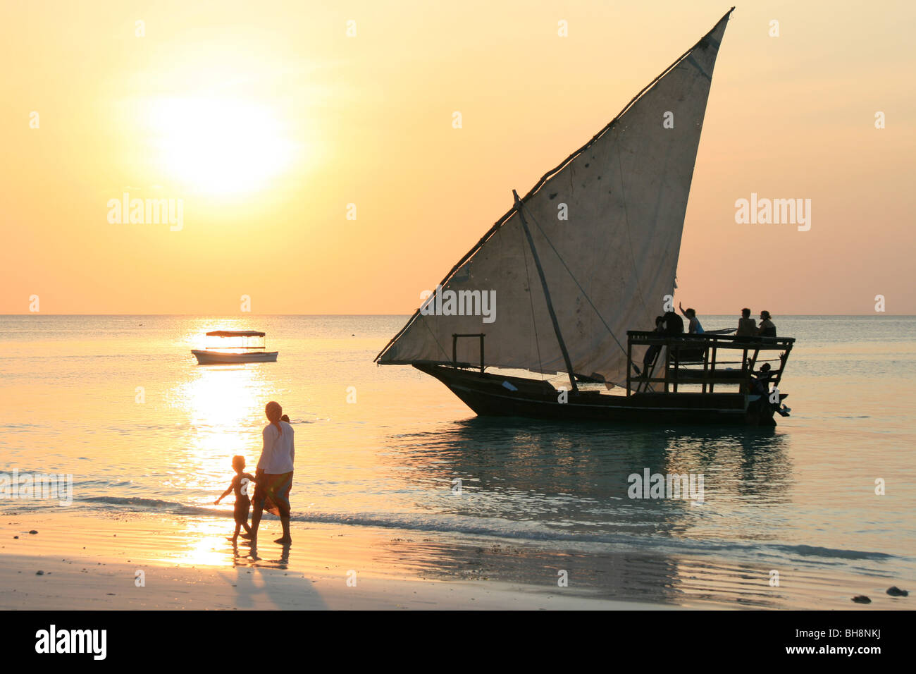a beach sunset on Zanzibar with dhow sailing boat taking tourists for a