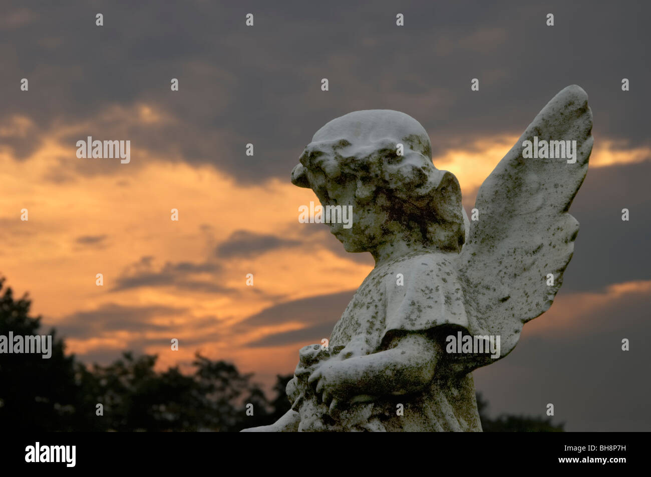 Small angel statue in a cemetery at sunset Stock Photo Alamy