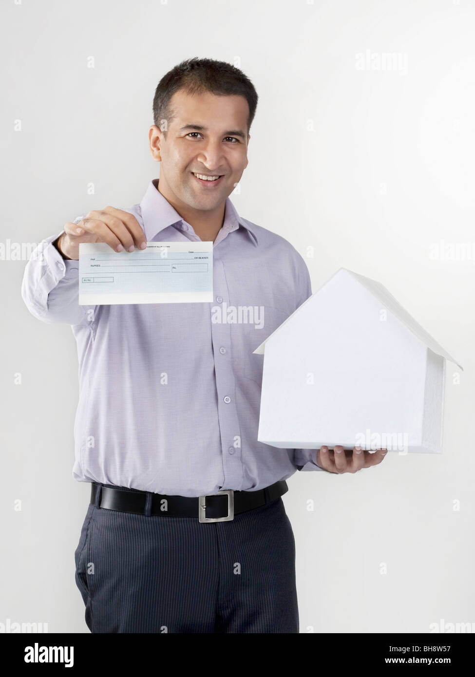 Man holding a house model and cheque Stock Photo