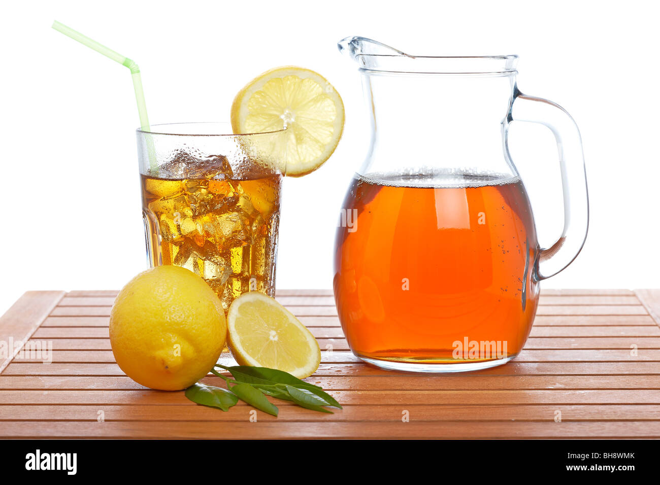 Ice tea pitcher and tumbler with lemon and icecubes on wooden background Stock Photo