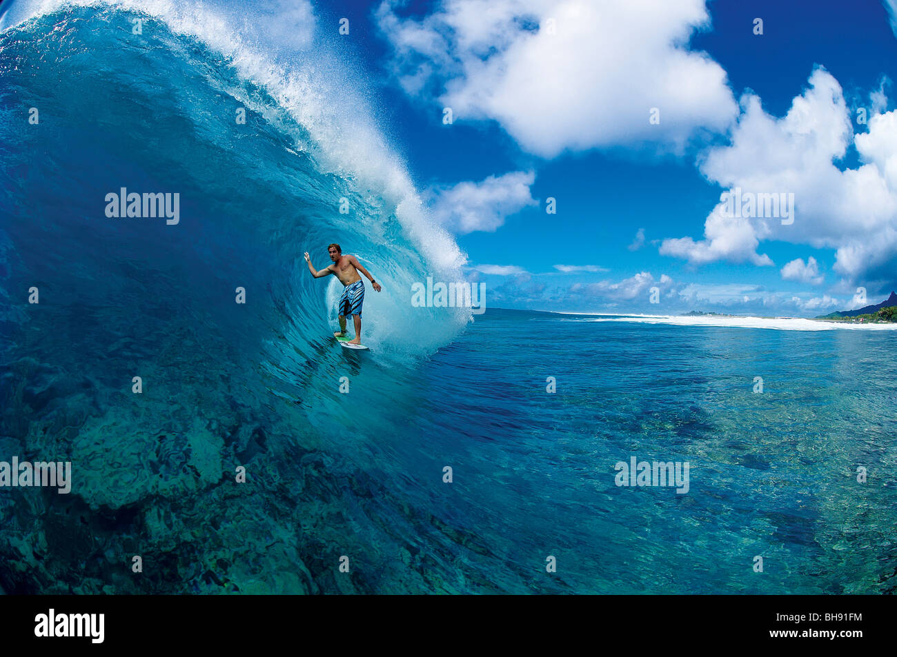 Surfer in the tube of large wave on a reef break in the Cook Islands Stock Photo