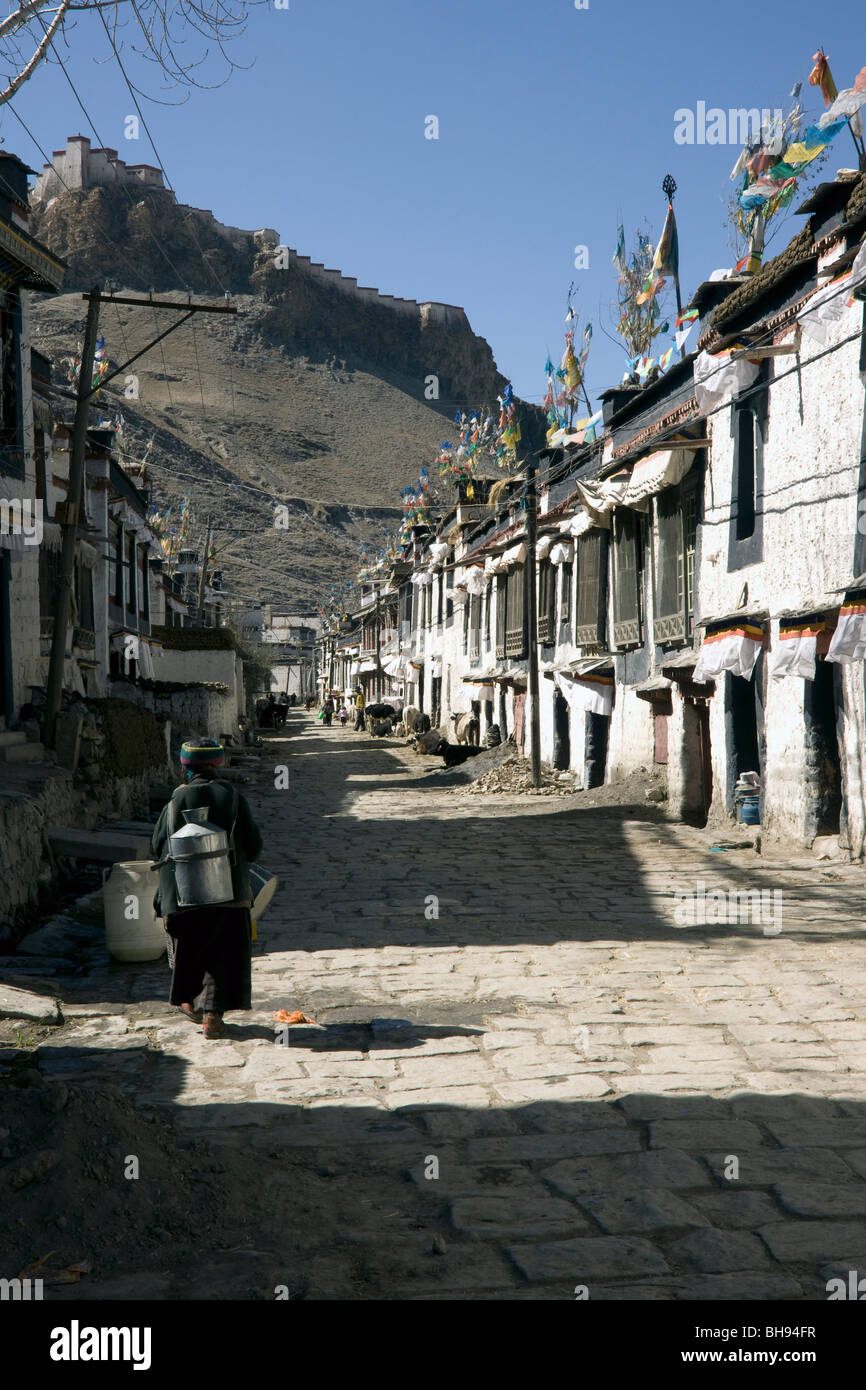 tibetan woman in the traditional old quarter of gyantse with the dzong on a hill in the distance Stock Photo