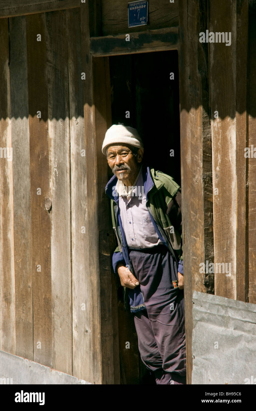 old tibetan man in the doorway of his house in the border town of zhangmu Stock Photo