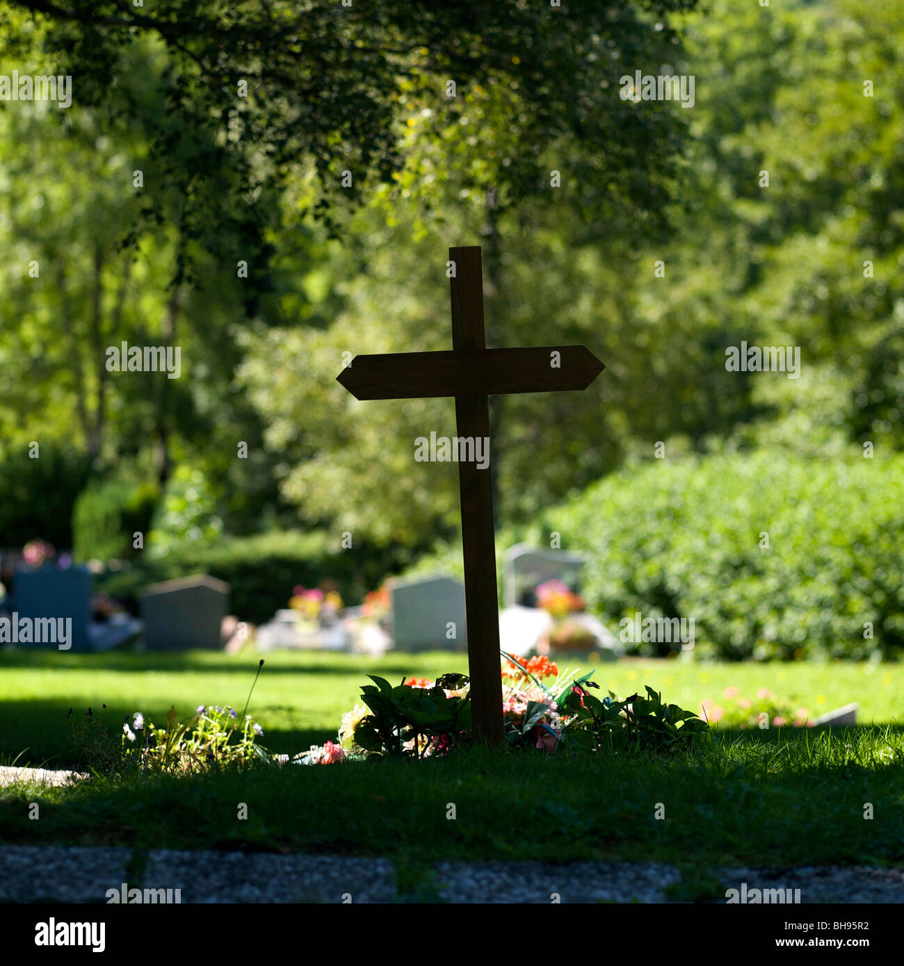 Cross of cemetery with flowers. Stock Photo