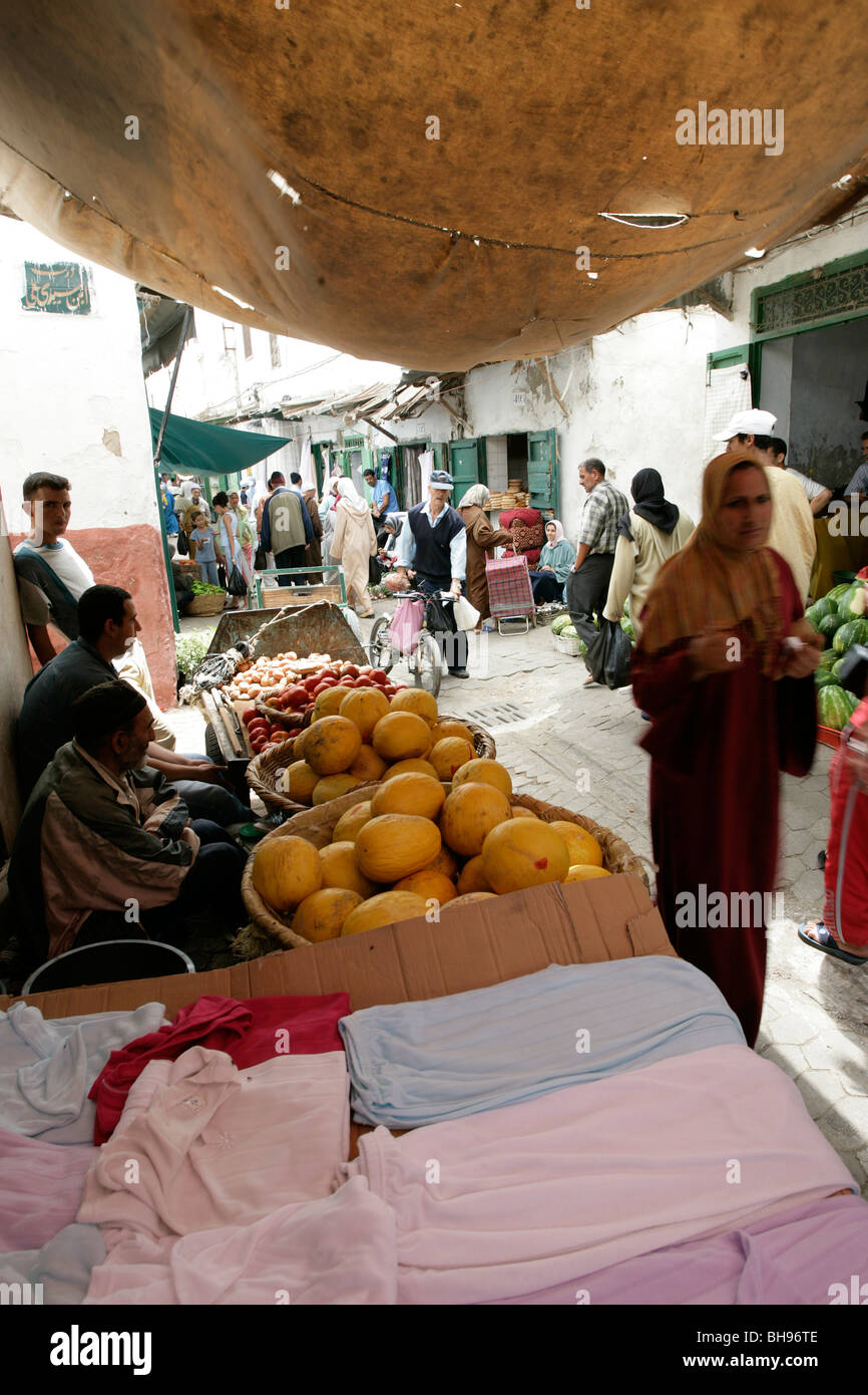 Fruit and clothing for sale at a stall along one of the many narrow allies at the casbah in Tetuon, Morocco Stock Photo