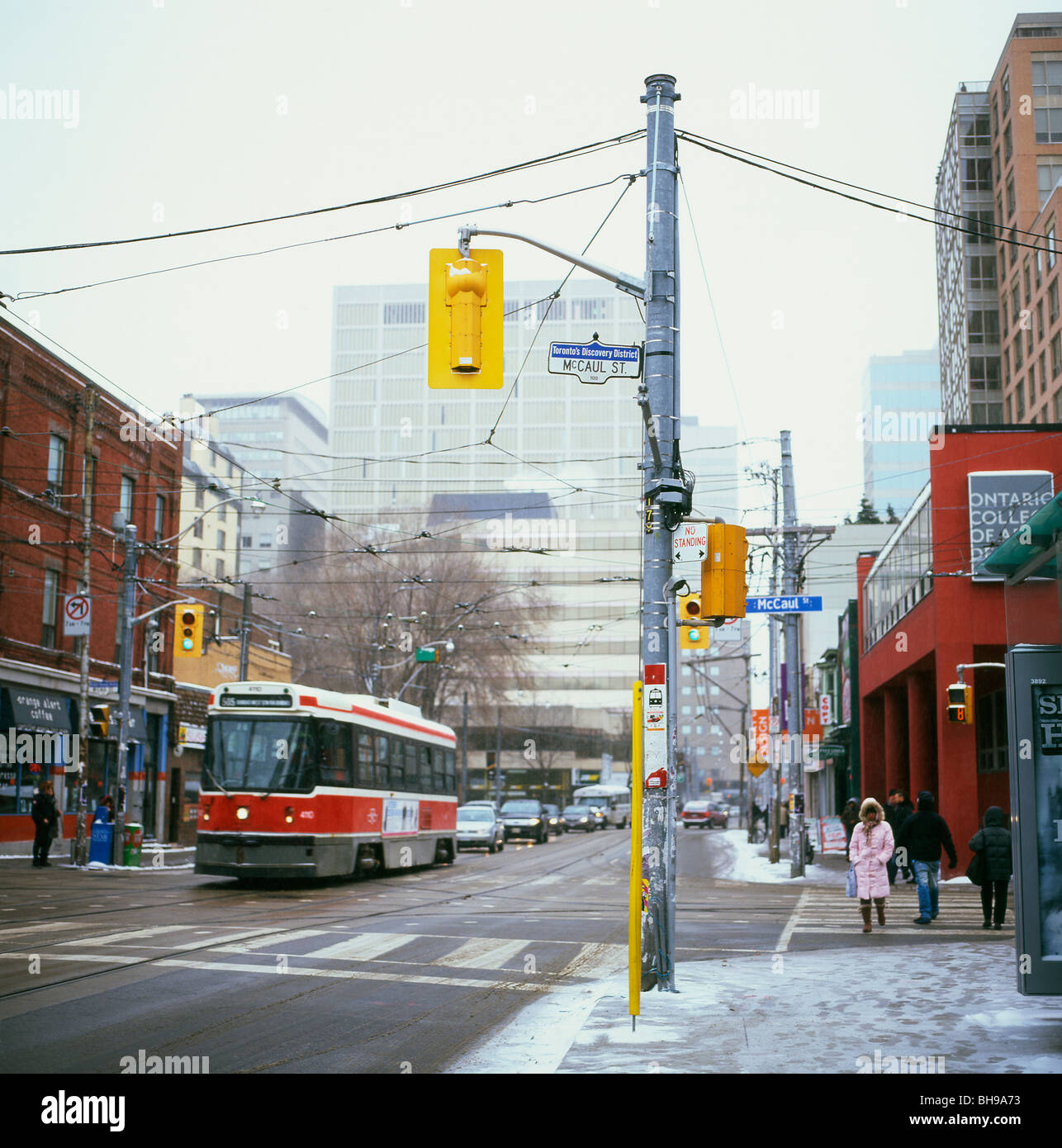 Tram on Dundas Street near McCaul Street in winter with snowy pavements and pedestrians Toronto, Ontario Canada Stock Photo