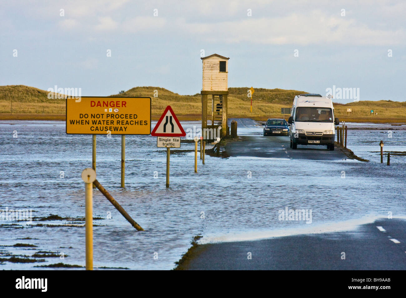 Tide coming in on Lindisfarne Crossing with 2 vehicles stuck Stock Photo