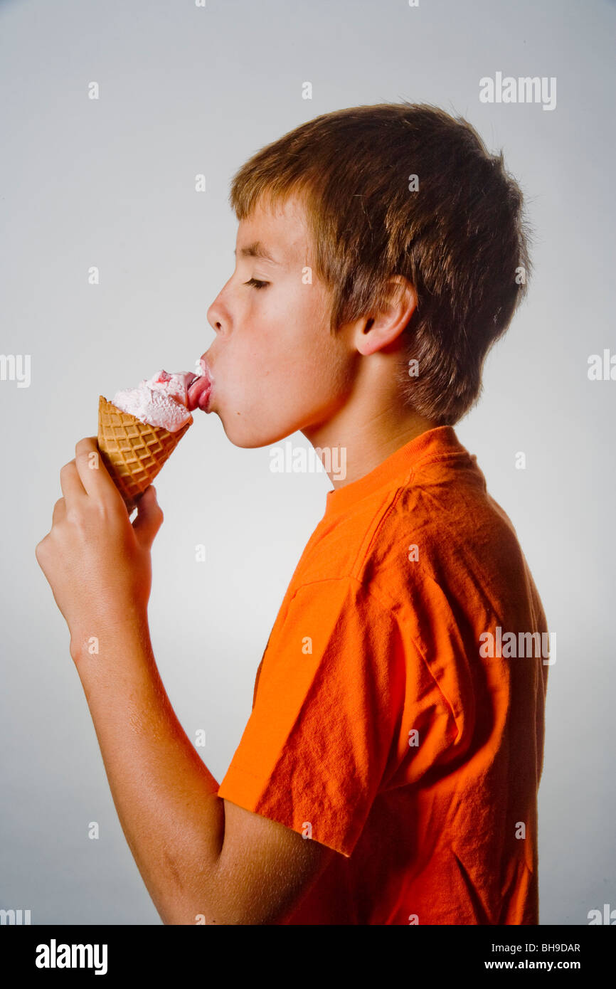 A happy ten year old boy licks a scoop of ice cream in a waffle cone