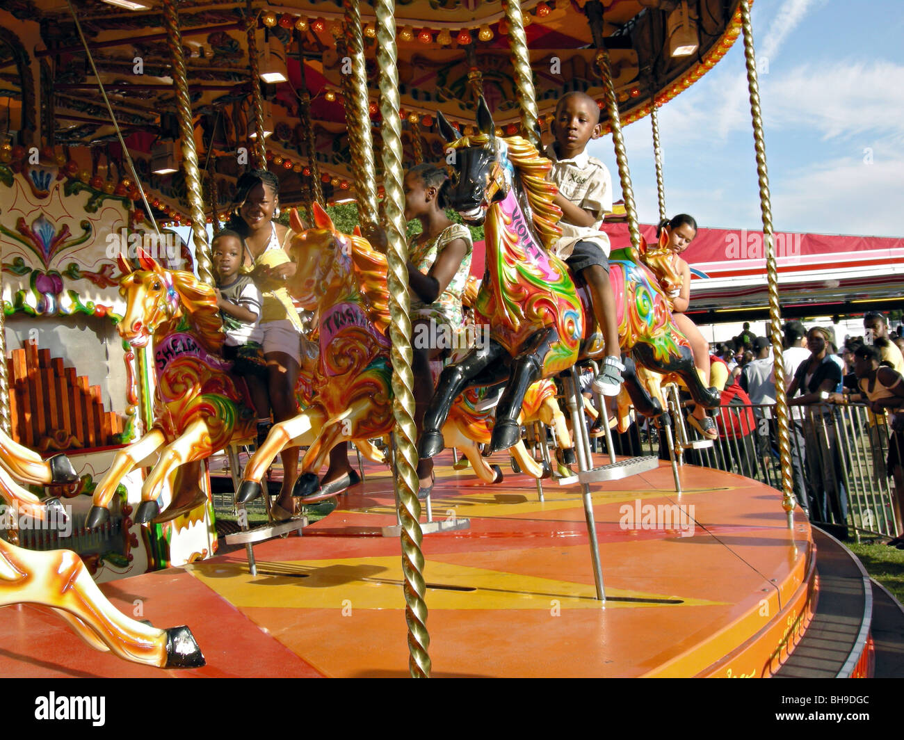 UK Afro caribbean Children riding toy horses at a funfair in south London Stock Photo