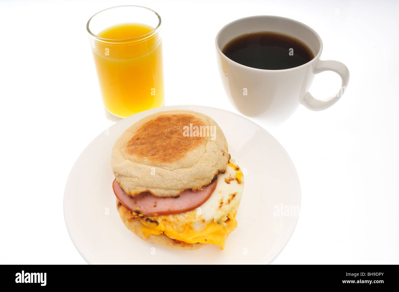 Egg, cheese and canadian bacon breakfast english muffin sandwich with glass of orange juice and