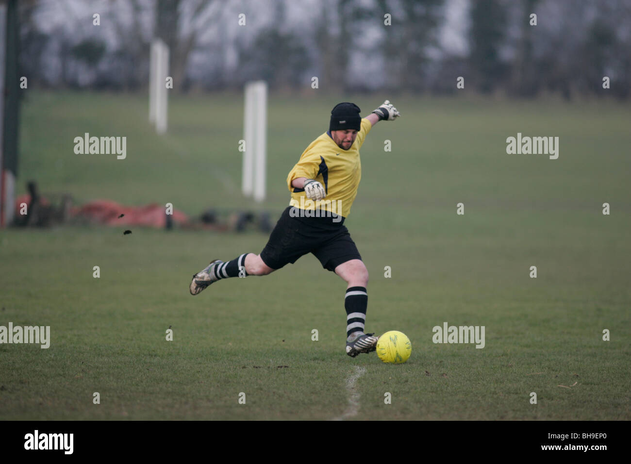 A goalkeeper playing local league football (soccer) keeps warm by