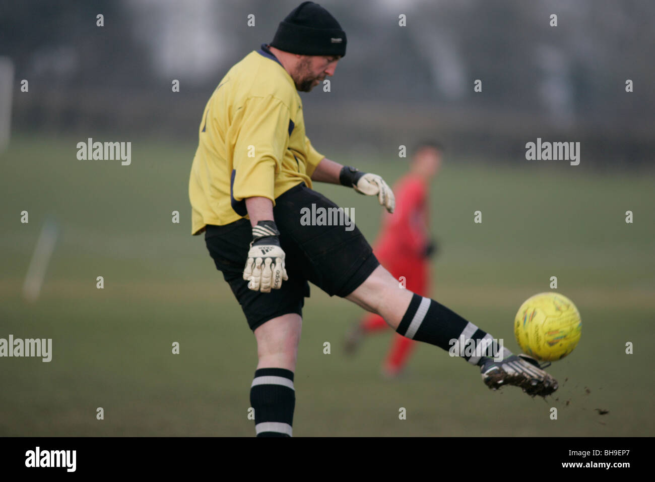 A goalkeeper playing local league football (soccer) keeps warm by
