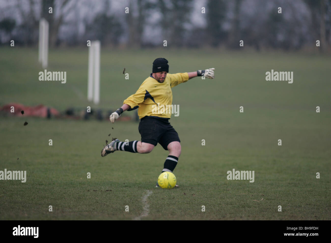 A goalkeeper playing local league football (soccer) keeps warm by