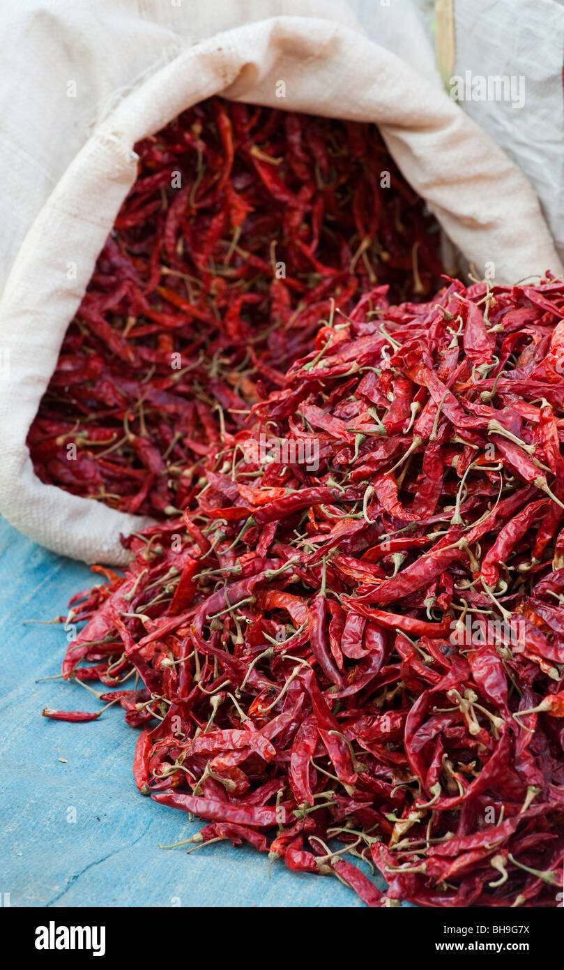 Dried red chillis in and out of a sack at an Indian market. Andhra Pradesh, India Stock Photo