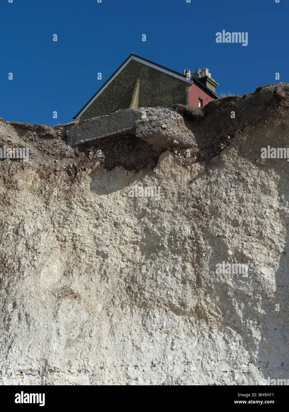 house on cliff edge due to erosion by sea. Stock Photo