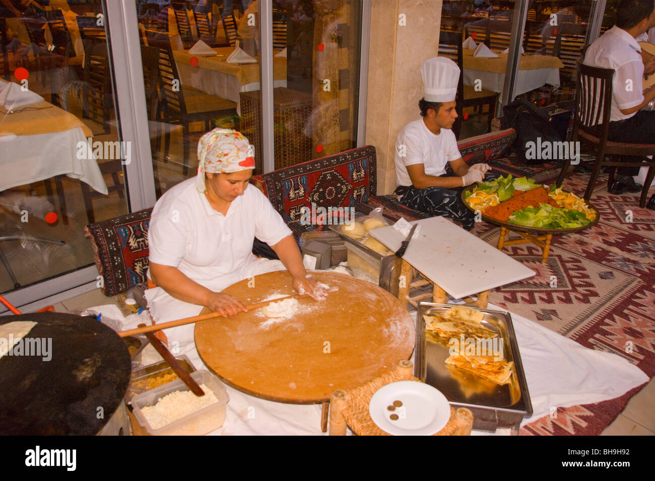 Turkish lady demonsrates local pastry making techniques on large bread board Stock Photo