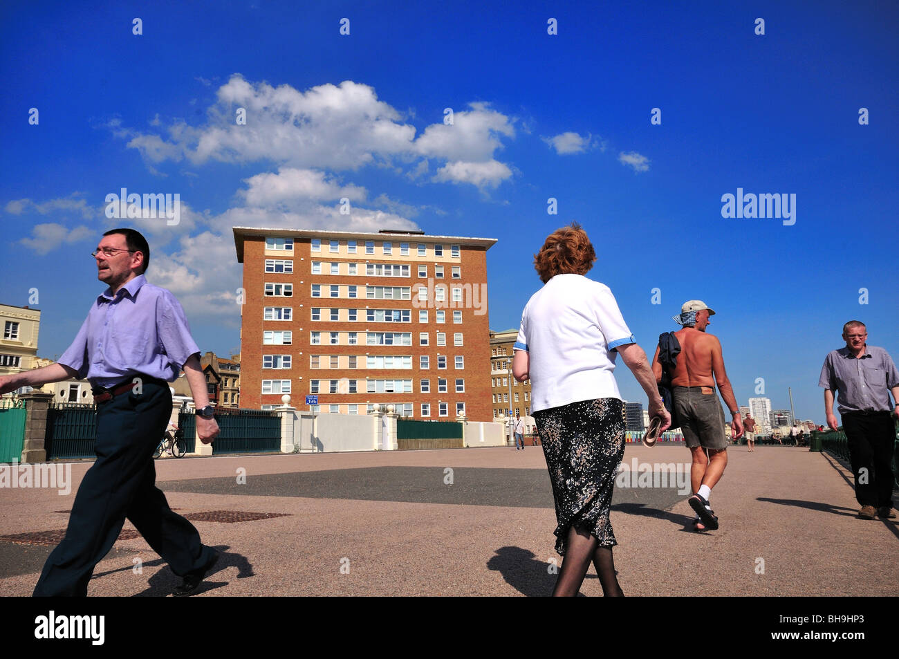 People walking on the Brighton and Hove seafront promenade in summer ...