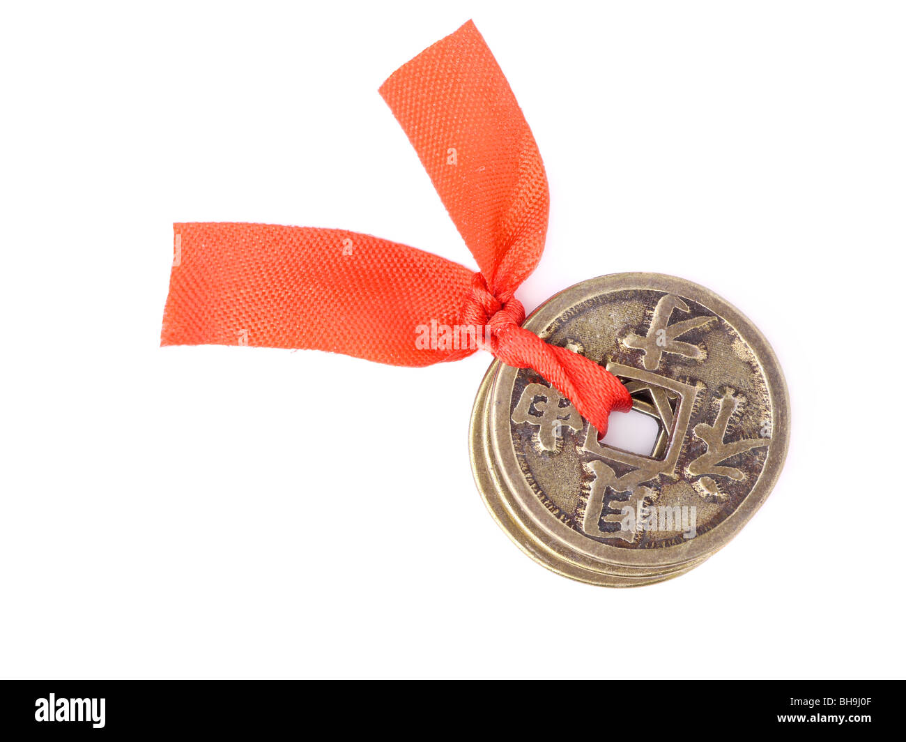 Three Chinese coins of luck tied with red ribbon symbolizing prosperity and fortune - shot over white background Stock Photo
