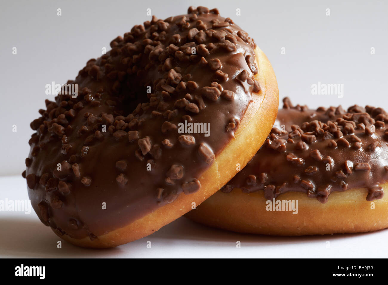 two chocolate ring donuts set against white background Stock Photo