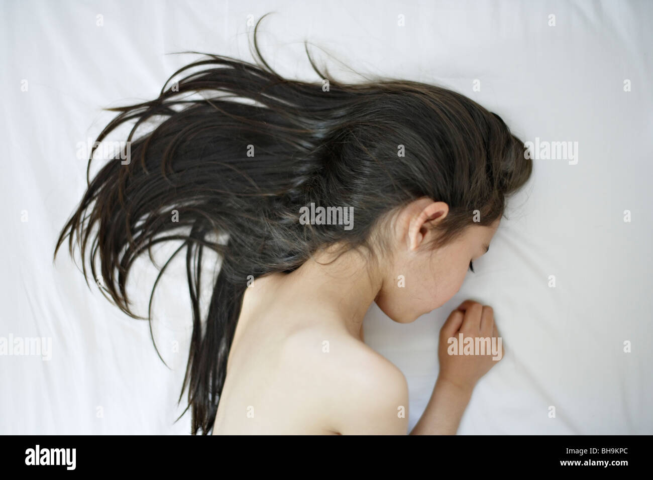 Six year old girl lies on bed Stock Photo