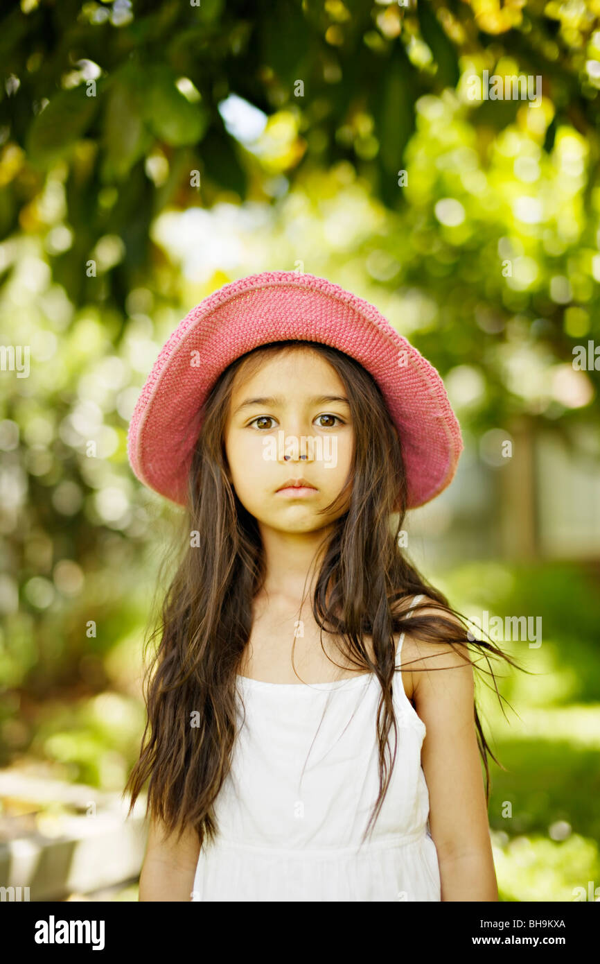 Six year old girl wearing pink hat  outdoors in a garden Stock Photo