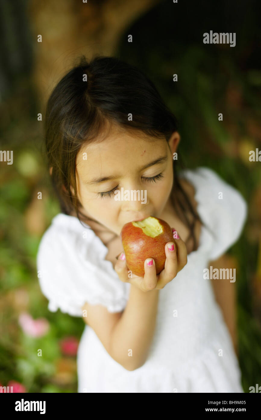 Six year old girl bites into apple Stock Photo