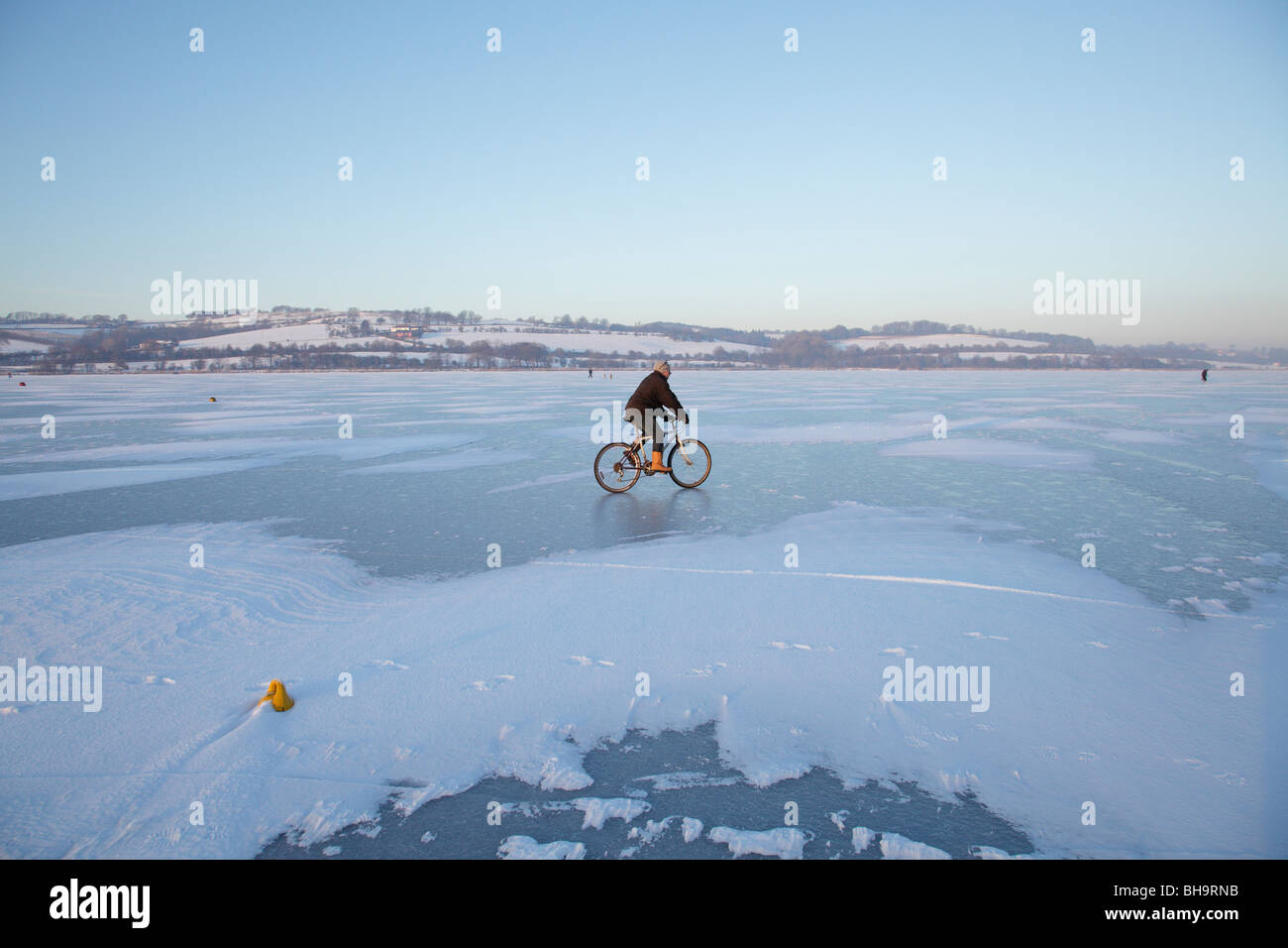 A man cycling on a frozen Castle Semple Loch, at Lochwinnoch in Renfrewshire, Scotland, UK Stock Photo