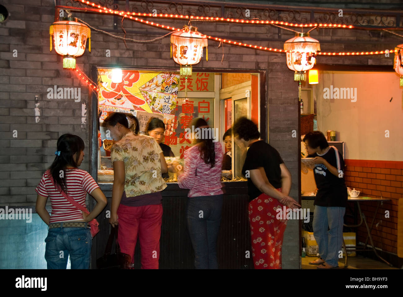 Beijing, CHINA- Hutong Neighborhood, Lit up at Night, 'Chinese Restaurant' Women Ordering at Window of Take out Shop, Small Shop Night, women friends china city Stock Photo